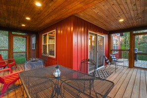 Een overdekte patio met houten plafond, rode muren en een tafel met stoelen.