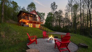 A cabin with a deck, outdoor seating, and a fire pit.