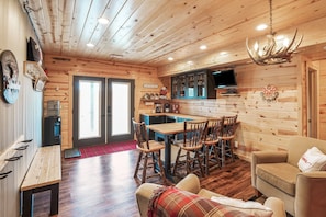 Un acogedor interior de cabaña con una zona de comedor de madera, una barra para café y un televisor.