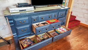 A blue dresser with multiple drawers, a television on top, and various board games and toys in the drawers.