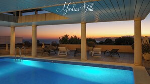 Zona de piscina en la azotea con vistas a la puesta de sol y montañas.