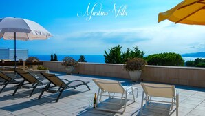 Una terraza en la azotea con sillones de descanso, sombrillas y plantas en macetas.