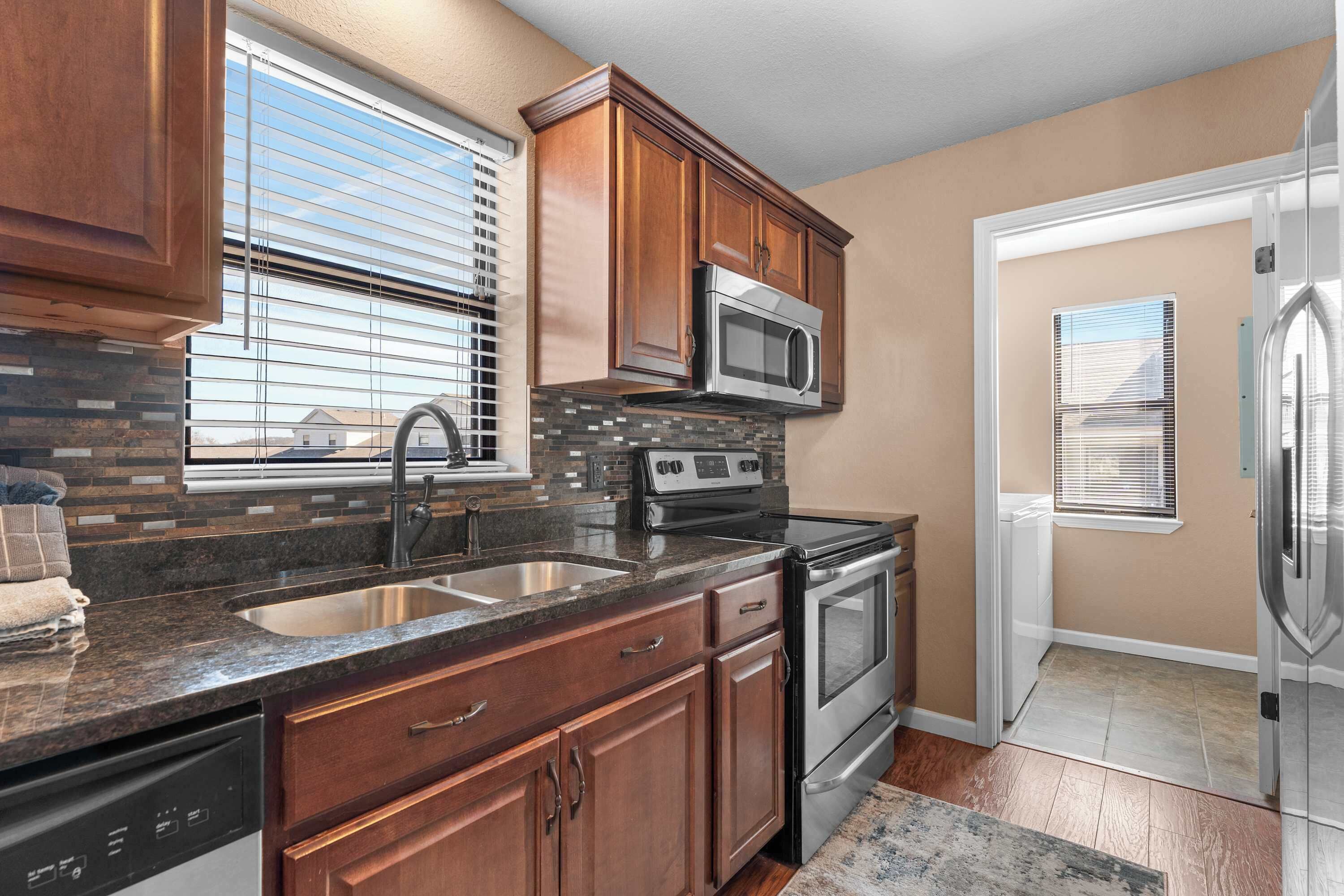 A kitchen with wooden cabinets, a stainless steel microwave, a stove, and a dishwasher.