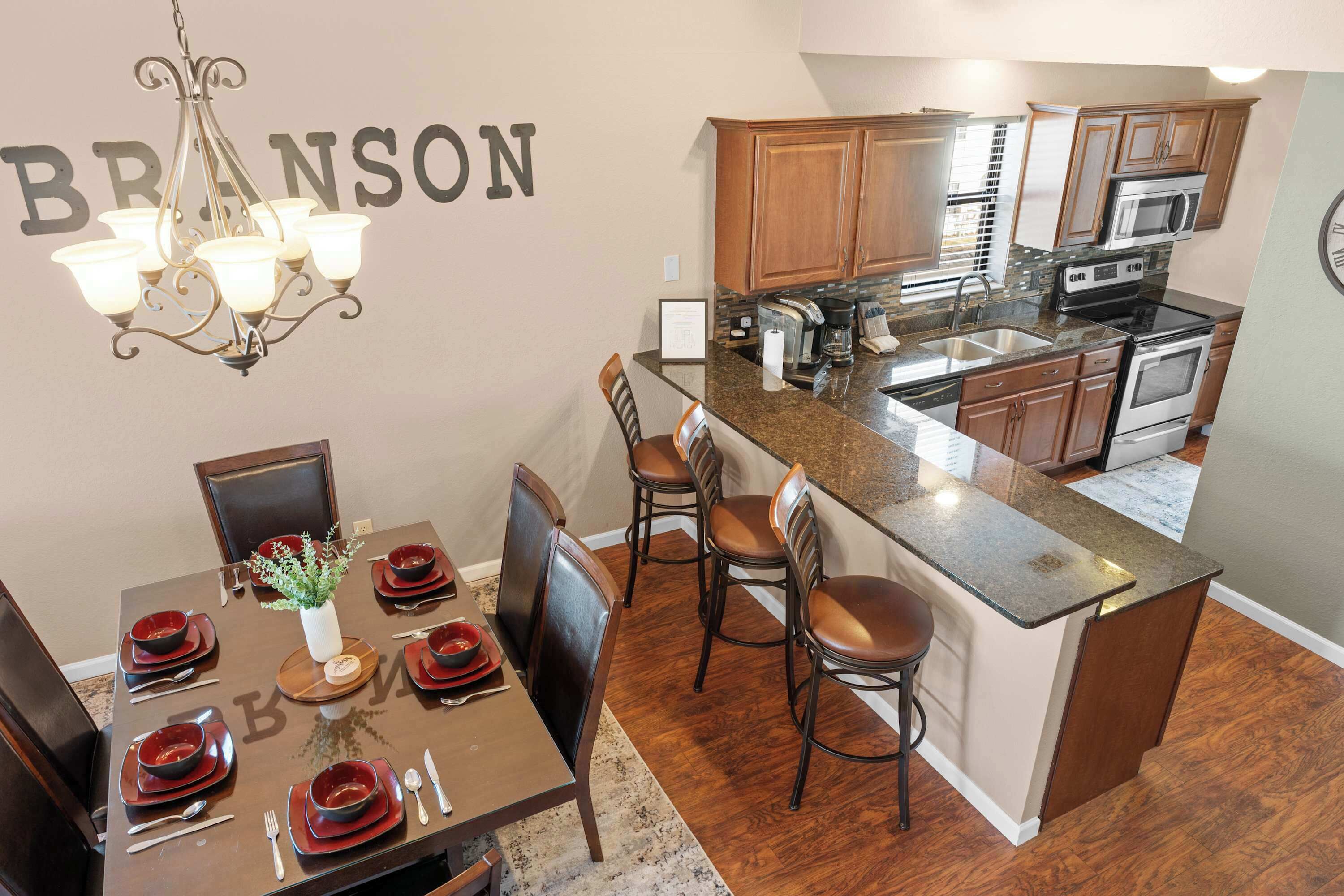 A modern kitchen with granite countertops, wooden cabinets, and stainless steel appliances.