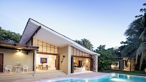 A modern house with a swimming pool, outdoor seating, and a stone wall. - Yeguas V43 by Wynwood House (Anapoima)