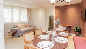 A modern dining area with a round table set for four, a sofa, and a television mounted on the wall. - Elegant Apartment St Germain des Pres Luxembourg Park (Paris)