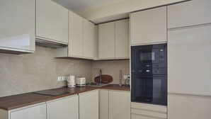 A modern kitchen with white cabinets, a wooden countertop, a built-in microwave, and a coffee maker. - Elegant Apartment St Germain des Pres Luxembourg Park (Paris)