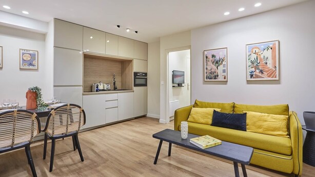 Un salon moderne comprenant un canapé, une table basse et un coin repas avec des chaises et une table.