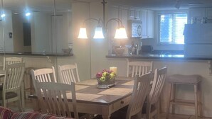 A dining area with a wooden table, chairs, and a fruit basket.