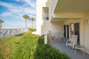 A balcony with outdoor seating, a small window, and a view of the pool and palm trees. - Pier Point South Ocean View Condo D-47 (St. Augustine)