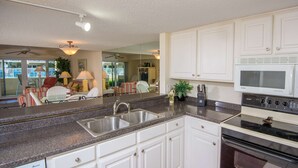 A kitchen with white cabinets, a granite countertop, a double sink, a microwave, and an oven.