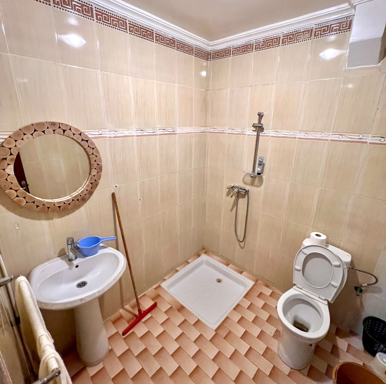 Een badkamer met een wastafel, toilet, douche en een spiegel met decoratieve lijst.