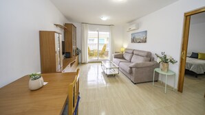 A modern living room with a sofa, a dining table, and a small side table with a plant. - HomeHolidaysRentals Belisa - Costa Barcelona (Pineda de Mar)