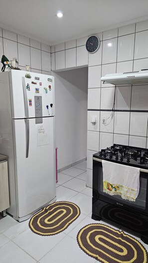Una cucina compatta con frigorifero, fornello e orologio a parete.