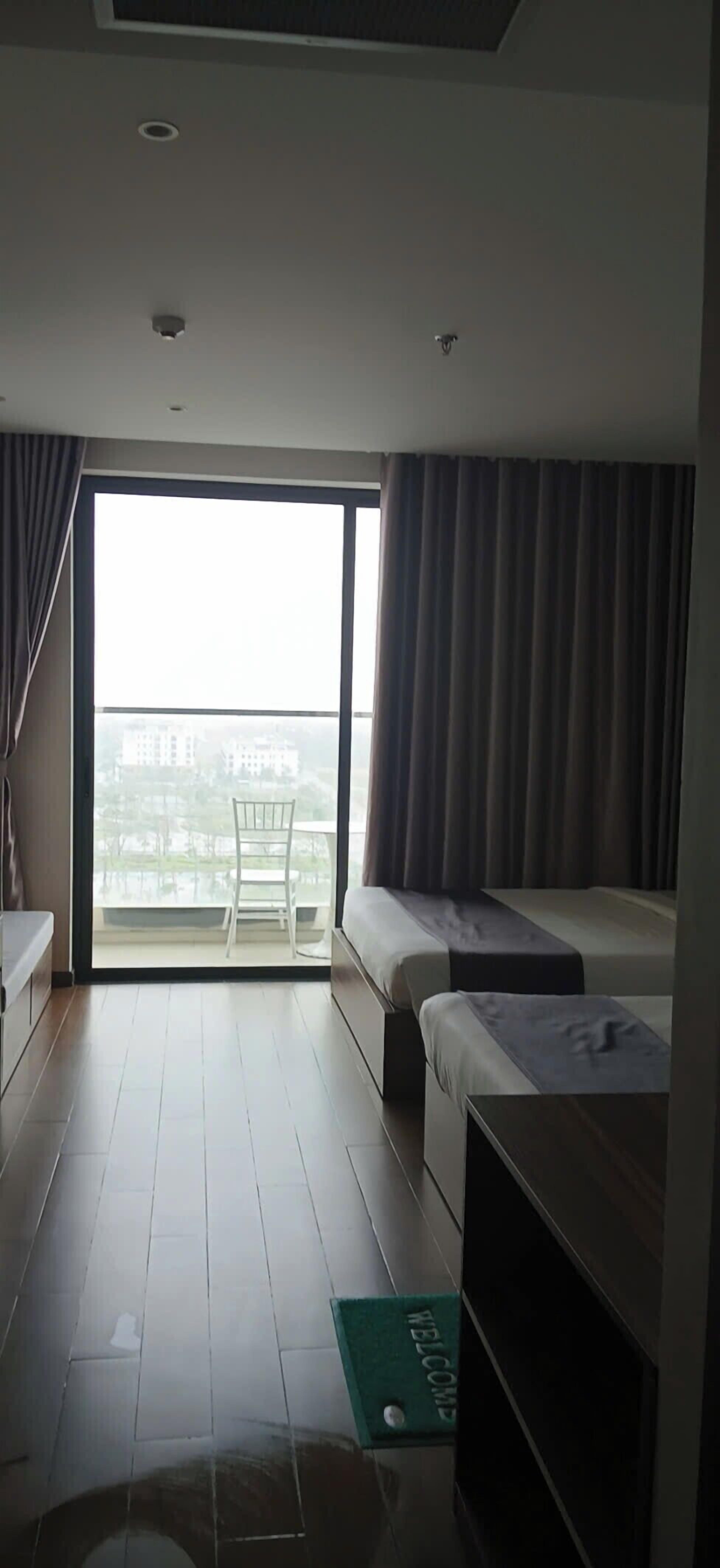 Een hotelkamer met balkon, een bed, bureau en stoel.