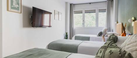 Una habitación de hotel con dos camas, un televisor, una ventana con cortinas y un cuadro en la pared.