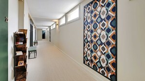 A hallway with a patterned wall, a seating area with a bench, and a door at the end. - Modern "green Suites" Residence - Meudon/velizy (Meudon)