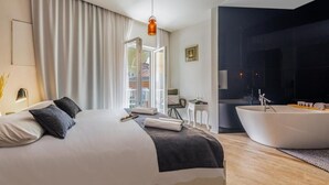 A modern hotel room with a large bed, a bathtub, and a view of the city. - Luxury rooms in Old Town (Zadar)