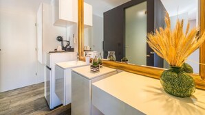 A modern bathroom with a white vanity, a large mirror, and a decorative vase with dried plants. - Luxury rooms in Old Town (Zadar)