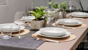 A neatly set dining table with white plates, clear glasses, and a small potted plant.