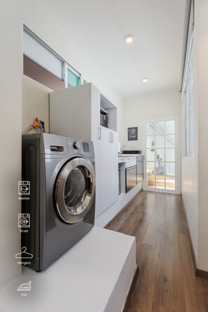 A laundry area with a washing machine, dryer, and ironing station.