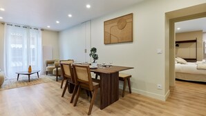Un coin repas avec une table et des chaises en bois, une plante en pot et un tableau accroché au mur.