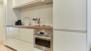 A modern kitchen with stainless steel appliances, a wooden countertop, and white cabinetry.