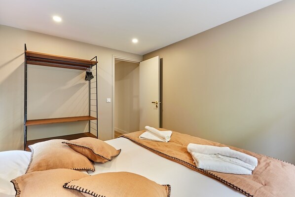 A bedroom with bunk beds, a wooden ladder, and a door leading to another room.