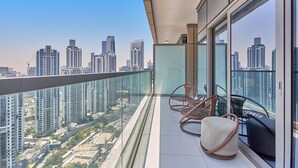Een balkon met uitzicht op de stad, rieten stoelen en een glazen balustrade.