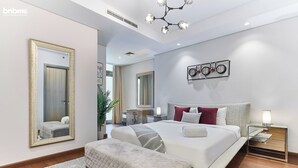 Een moderne slaapkamer met een groot bed, nachtkastjes, een spiegel en een wandklok.