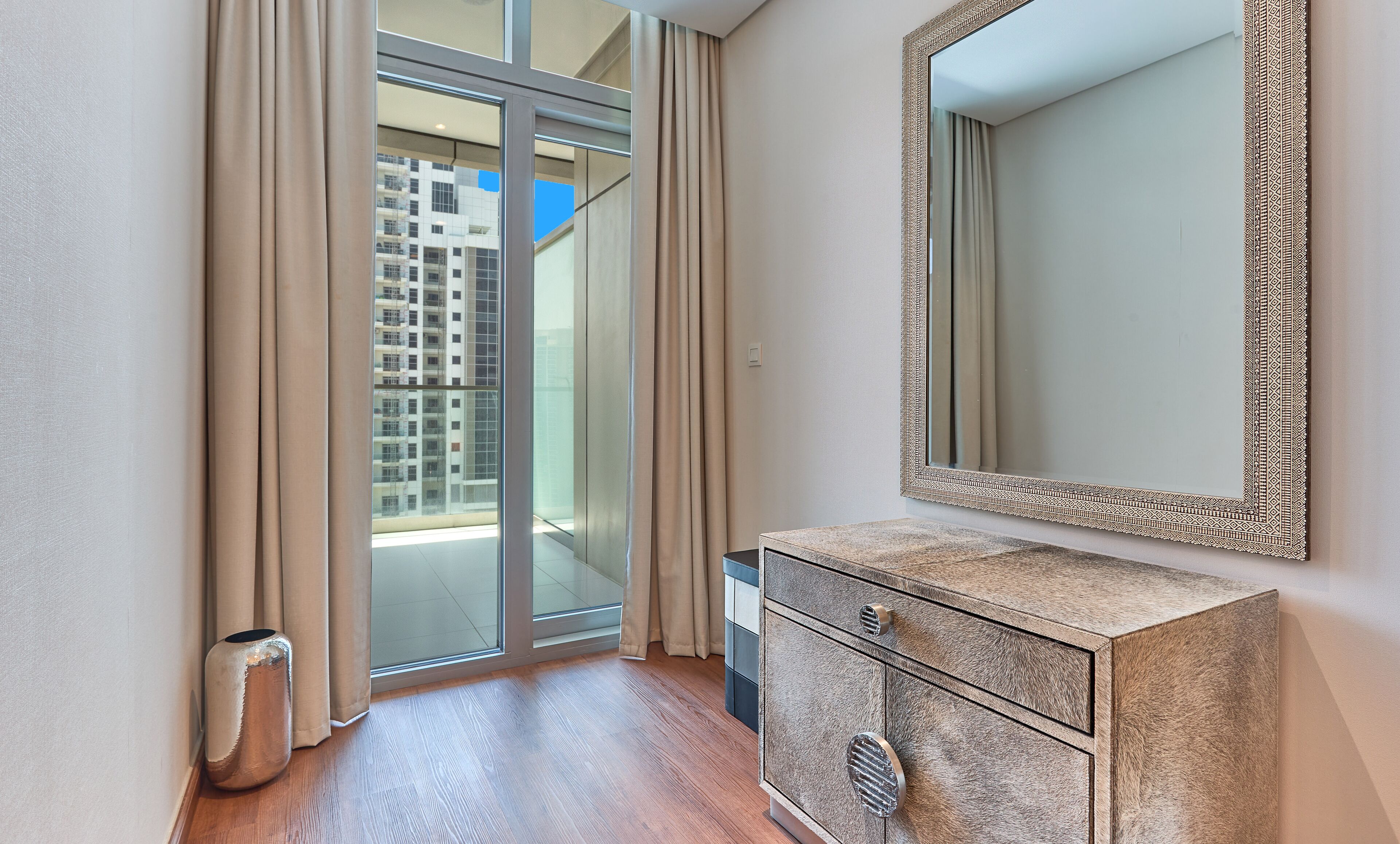 A modern bathroom with a large mirror, a wooden cabinet, and a sliding glass door leading to a balcony.
