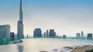 Een hoog gebouw met een modern ontwerp, omringd door andere wolkenkrabbers.