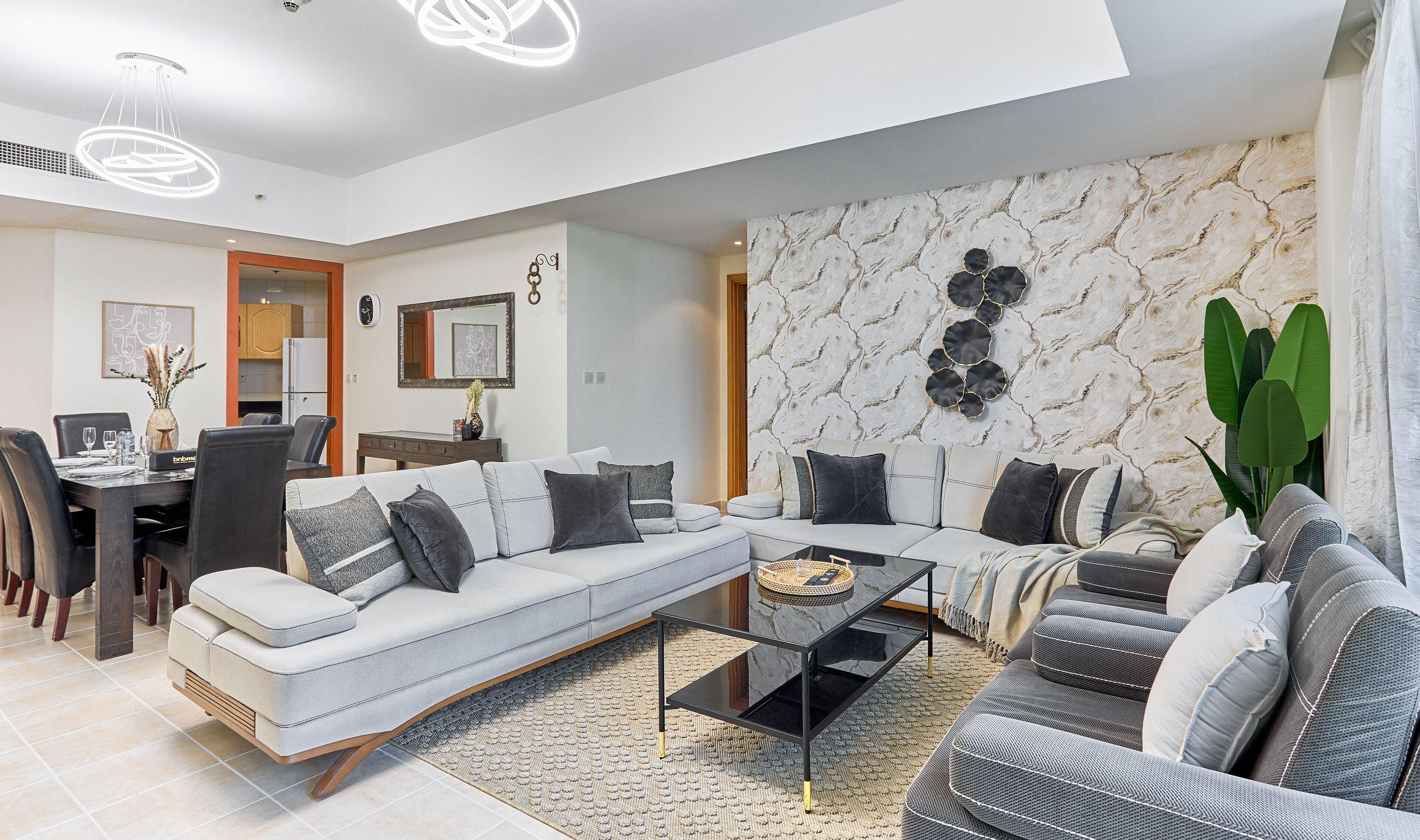 A modern living room with a sectional sofa, a coffee table, and a dining area.