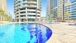 Ein modernes Hotel mit Schwimmbad, Hochhäusern und Palmen.