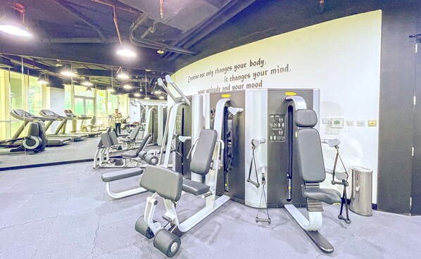A gym with various exercise machines, a treadmill, and a motivational quote on the wall. - bnbme | Damac Waves Tower | 3 + Maids (Dubai)