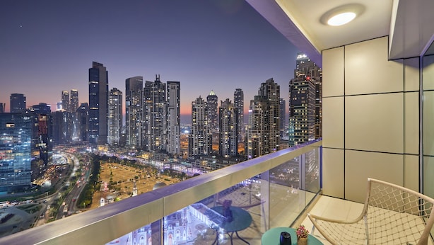 A balcony with a city view, a table with a plant, and a chair. - bnbme | 8 Boulevard Walk | Studio (Dubai)