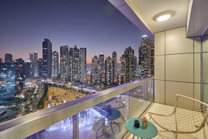 Ein Balkon mit Blick auf die Stadt, ein Tisch mit einer Pflanze und ein Stuhl.