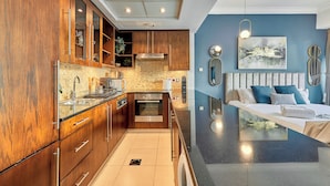 A modern kitchen with wooden cabinets, a built-in oven, and a large island with a sink. - bnbme | 8 Boulevard Walk | Studio (Dubai)