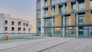 Ένα σύγχρονο κτίριο με γυάλινη πρόσοψη, εξωτερικό χώρο με καθίσματα και μια πισίνα.
