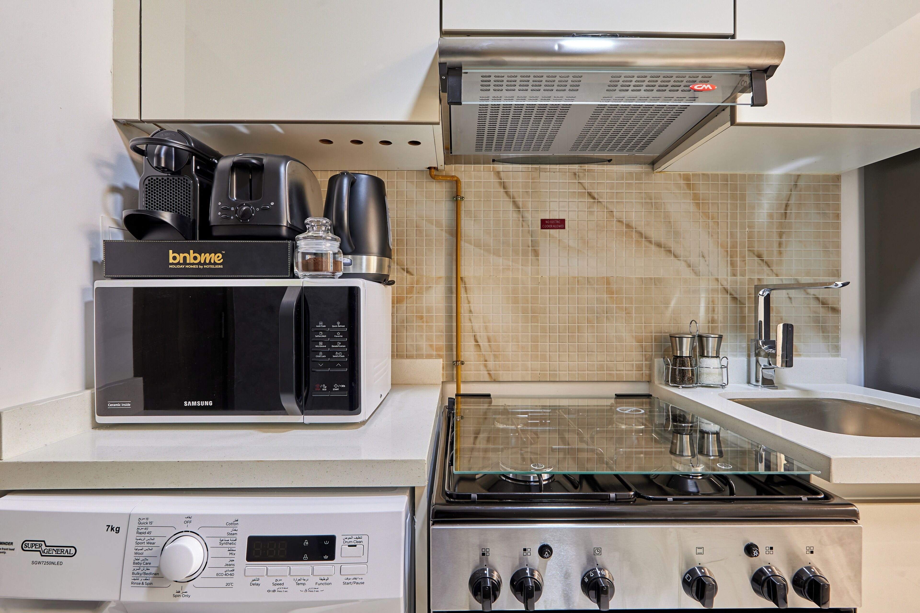A kitchenette with a microwave, coffee maker, and stove.