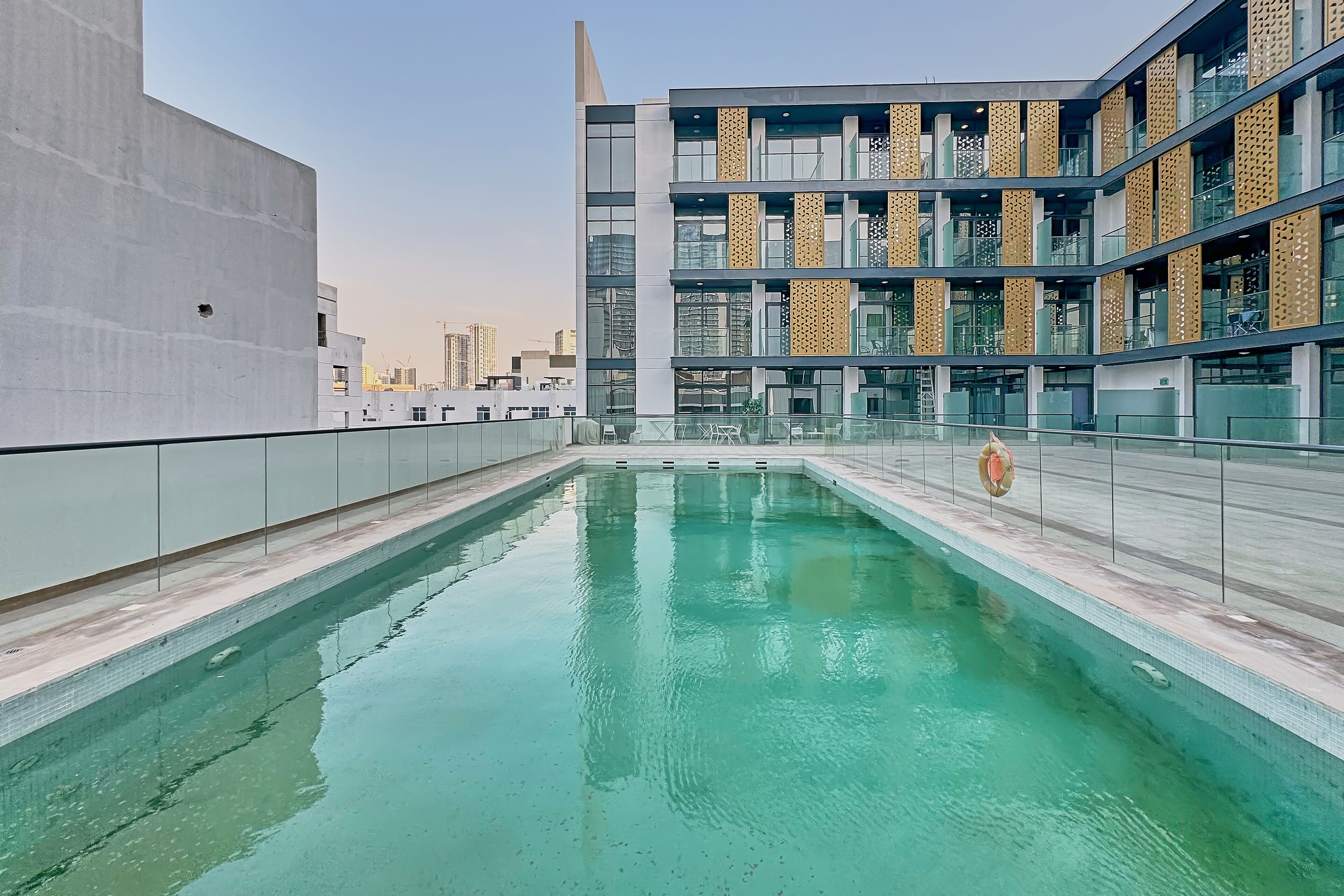 Un bâtiment moderne doté d’une piscine sur le toit, de grandes fenêtres et offrant une vue sur un ciel dégagé.