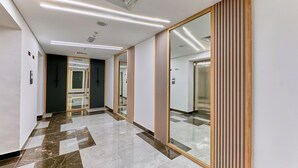 Un pasillo moderno con suelo de mármol, pared espejada y diseño de paneles de madera.