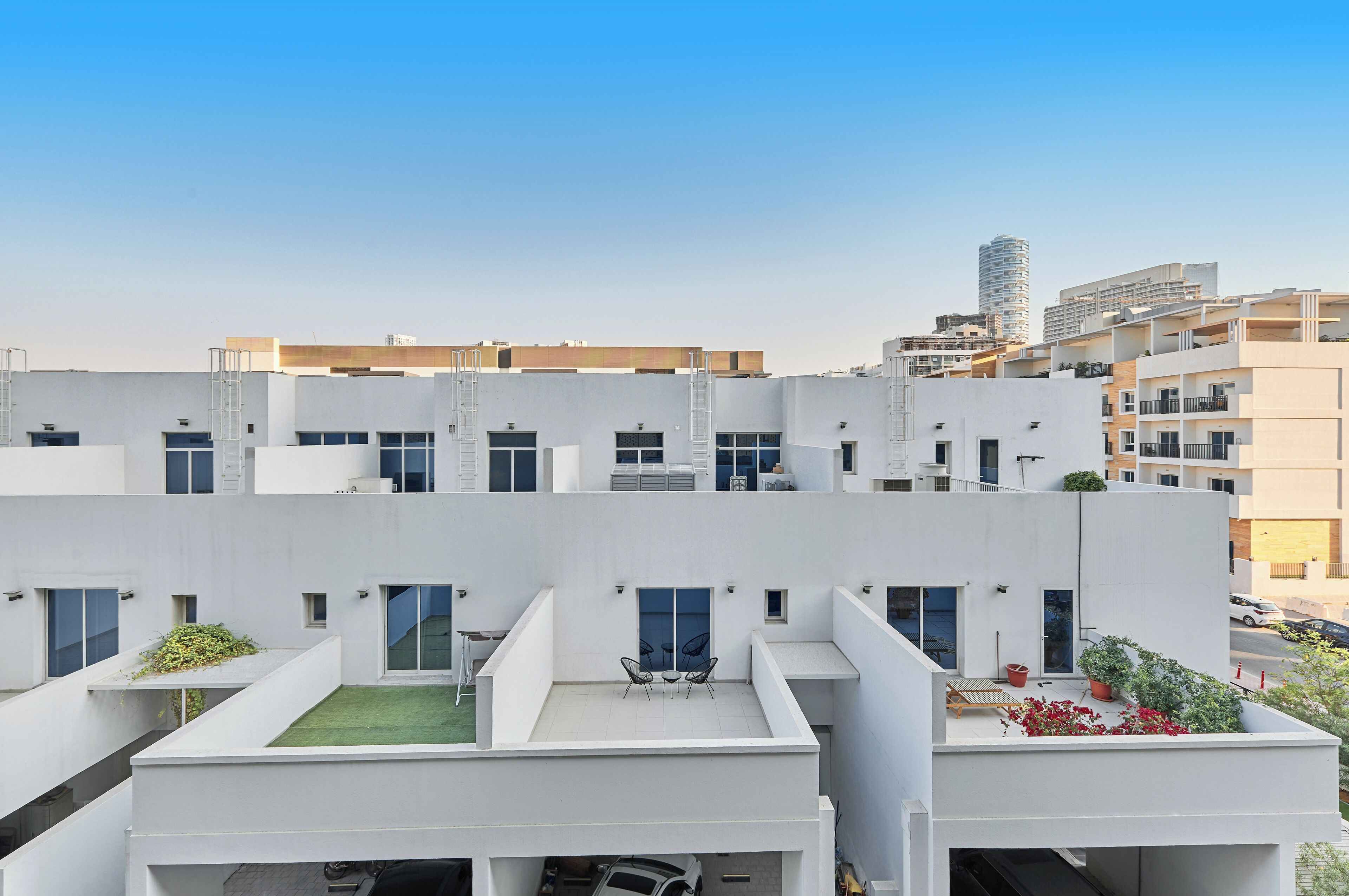 Un immeuble résidentiel moderne doté de nombreux balcons, d’un jardin sur le toit et offrant une vue dégagée sur le paysage urbain environnant.