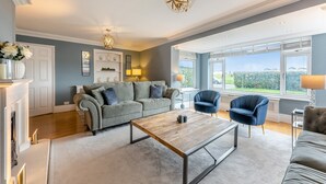 Ein modernes Wohnzimmer mit grauem Sofa, blauen Sesseln, einem Holztisch und einem Kamin.