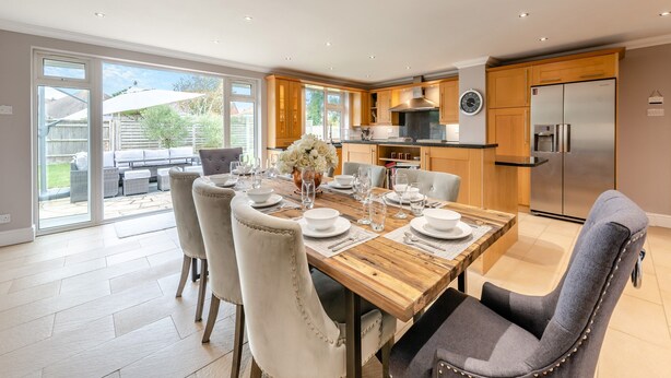 Eine moderne Küche mit Holzschränken, einem Edelstahlkühlschrank und einem Essbereich mit Holztisch und -stühlen.