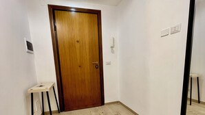 Un couloir avec une porte en bois, une petite table et un miroir accroché au mur.