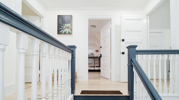 Una escalera con balaustres blancos y barandillas azules que conduce a una habitación con una cama y un cuadro en la pared.