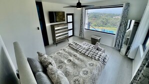 A bedroom with a bed, a ceiling fan, a TV, a window with a view, and a dresser. - Private Pickleball Oasis + Pool + 15 Min to Beaches & El Yunque, 30 Min Airport (Río Grande)