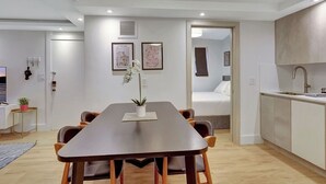 A modern, well-lit room with a dining table, chairs, a small potted plant, and a bed in the adjacent room. - Modern 2-Bedroom in Central South Beach Location (Miami Beach)
