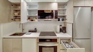 A modern kitchen with built-in appliances, open shelving, and a countertop with a coffee maker. - Modern 2-Bedroom in Central South Beach Location (Miami Beach)
